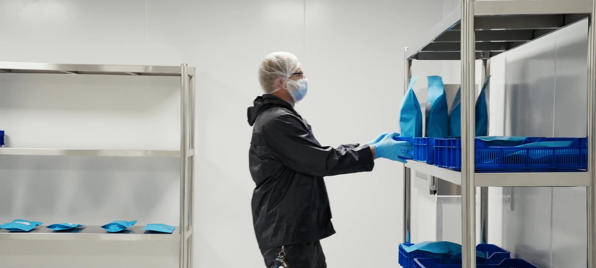 An operator in a gown loading bagged material onto stainless racking
